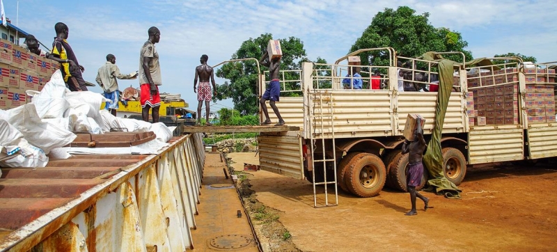 Продовольственная помощь загружается на баржу по реке Нил для доставки в отдаленные населенные пункты